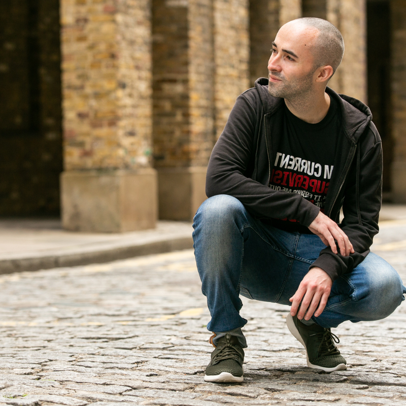Tom crouching on cobblestones, paused in thought